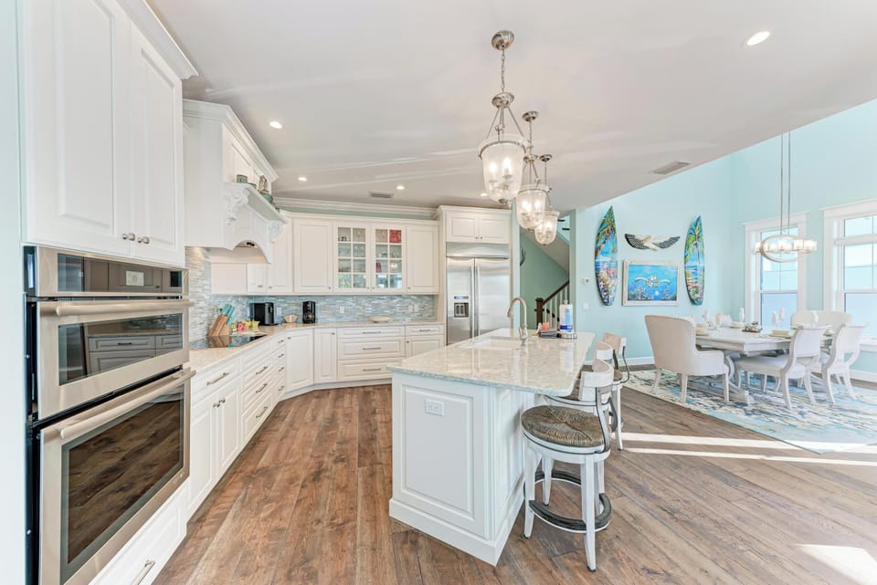Your gourmet kitchen awaits with granite counters, stainless appliances, and coastal charm flowing into the bright dining space.