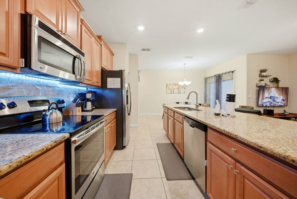 Experience a beautiful kitchen with warm wood cabinetry and sleek granite countertops, ideal for your cooking endeavors. Enjoy the inviting atmosphere created by under-cabinet lighting and the ease of stainless steel appliances.