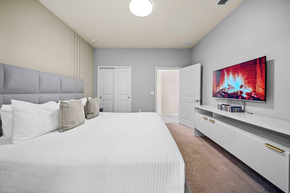 Relax in this beautifully designed bedroom featuring a plush king-size bed adorned with soft linens and decorative pillows. The sleek media unit and cozy electric fireplace create a tranquil atmosphere for your perfect retreat.