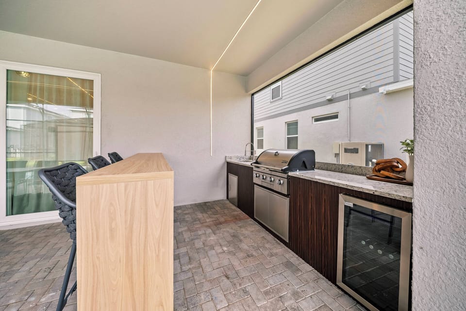 Experience a stunning outdoor kitchen with stylish stainless steel appliances and warm wood accents. Enjoy casual dining at the bar seating while savoring the fresh air in this perfect blend of style and functionality.