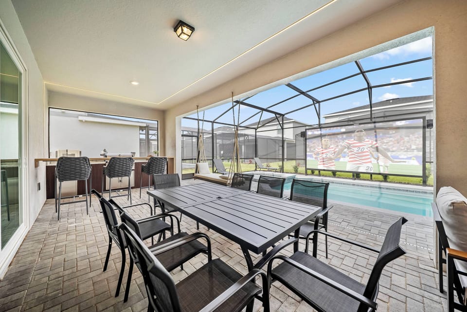 Welcome to the bright screened patio, featuring a stylish black dining set and cozy bar stools. Experience indoor-outdoor living with lovely views of the inviting pool, ideal for relaxation and gatherings.