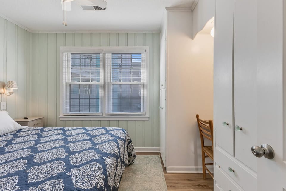 Rest peacefully in your charming bedroom with coastal cottage charm, featuring soft green paneling and abundant natural light.