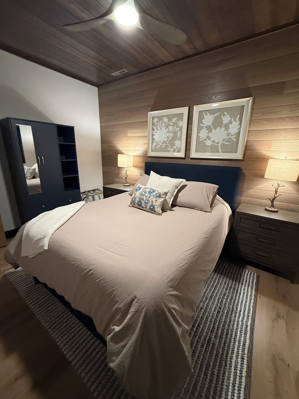 Master bedroom with armoire storage and two night stands.