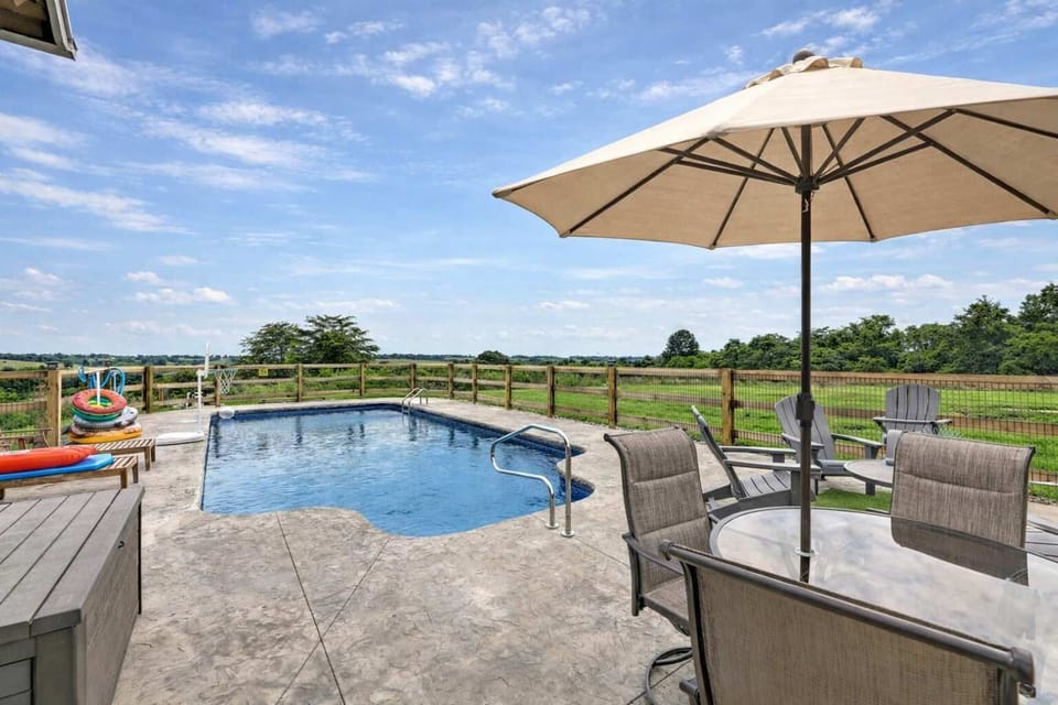 Private outdoor oasis with sparkling pool, sun loungers, and shaded dining under an umbrella. Enjoy peaceful countryside views, fresh air, and plenty of space to relax, unwind, or entertain.