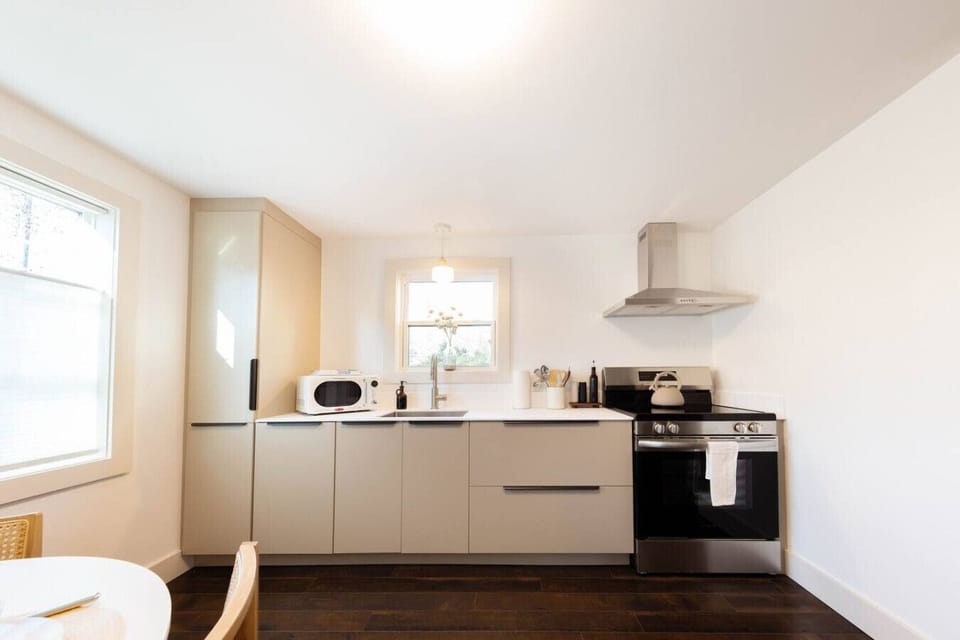 Sleek modern kitchen with induction cooktop, stainless steel appliances, microwave, and a SMEG drip coffee maker for easy mornings.