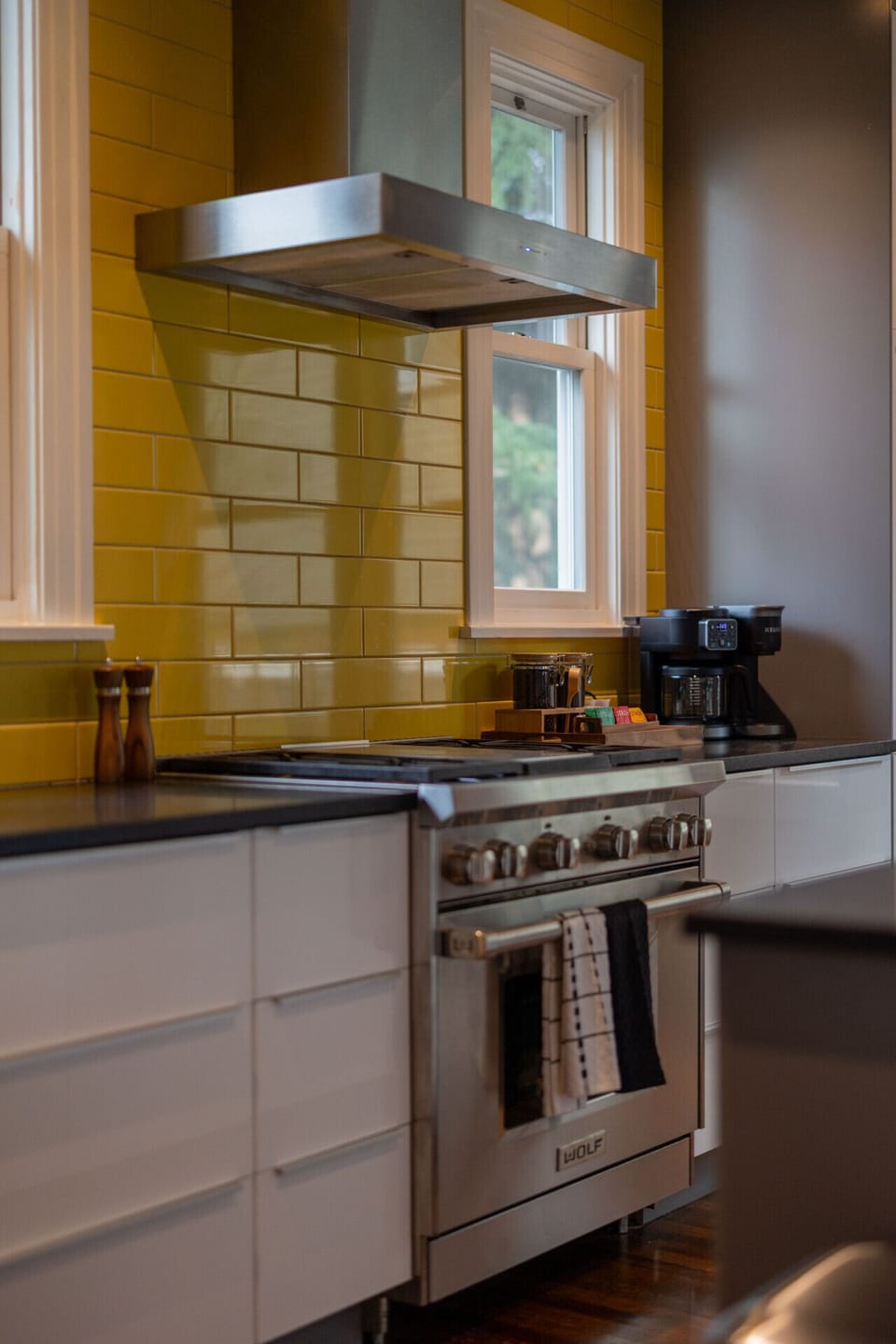 Chef’s kitchen with Wolf range, long island, and bold yellow tile backsplash.