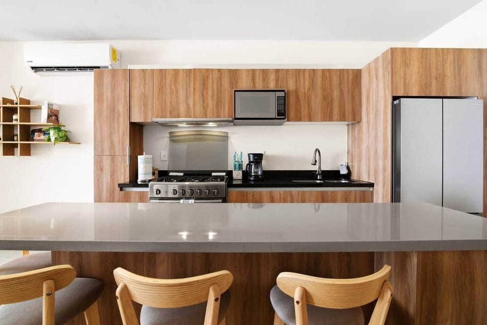 Fully equipped kitchen with all the amenities needed to prepare meals, including a stove and oven, microwave, blender, toaster, coffee machine, filtered drinking water and ice, plus a kitchen island with seating for four.