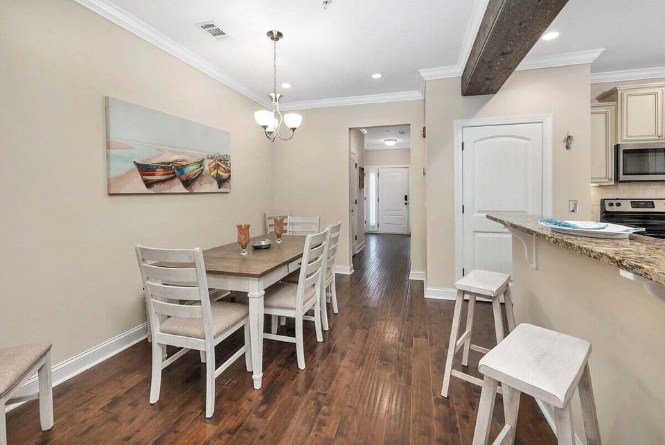 Dining area with wood table, white chairs, and pendant light