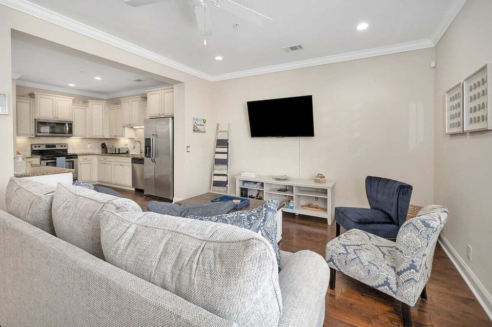 Living area with gray sofa, TV, and kitchen view