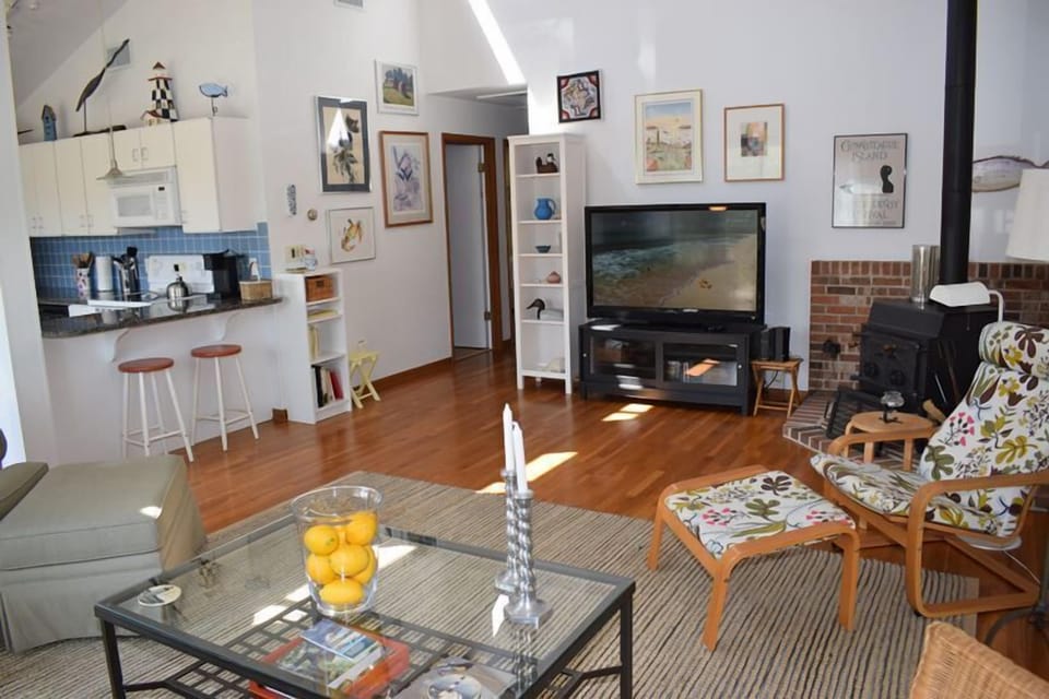 Living room features a cathedral ceiling and seasonal woodstove.
