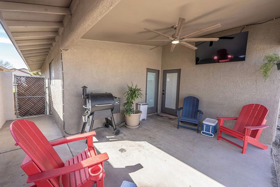 Covered back patio with outdoor TV, grill/smoker, fan, and recliner seating for relaxing evenings.