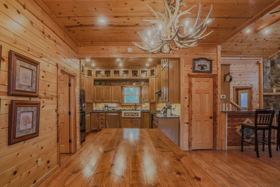 Stunning antler chandelier crowns the open kitchen and dining area