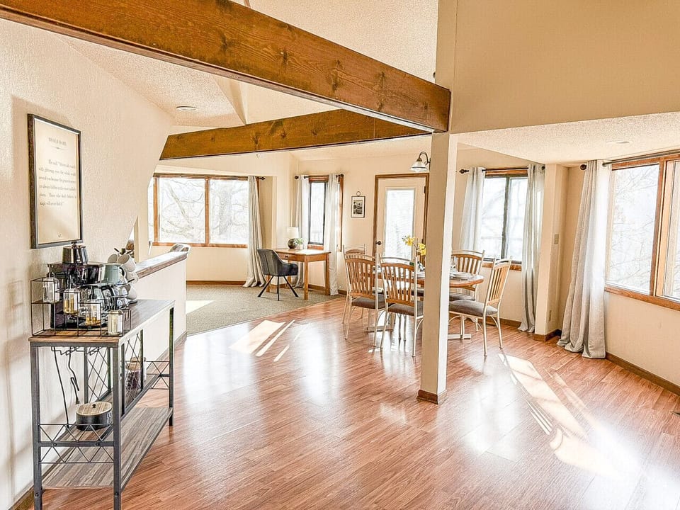 Spacious open living and dining area with vaulted ceilings, exposed wood beams, and abundant natural light—perfect for entertaining and relaxing in style.