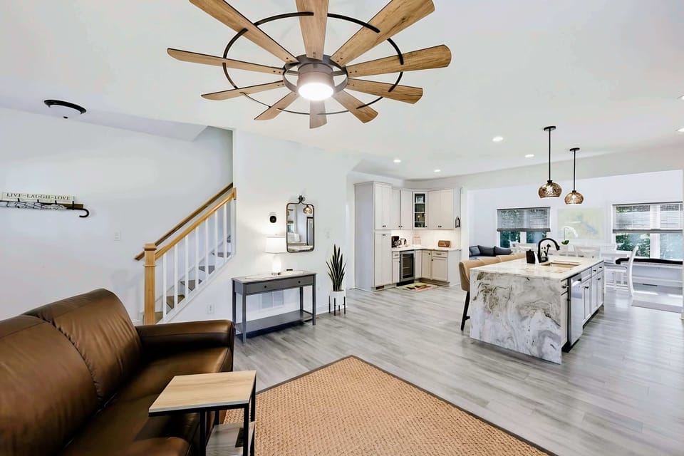 Living Room - Wide open-concept view flowing into the kitchen and dining, with a statement windmill fan overhead.