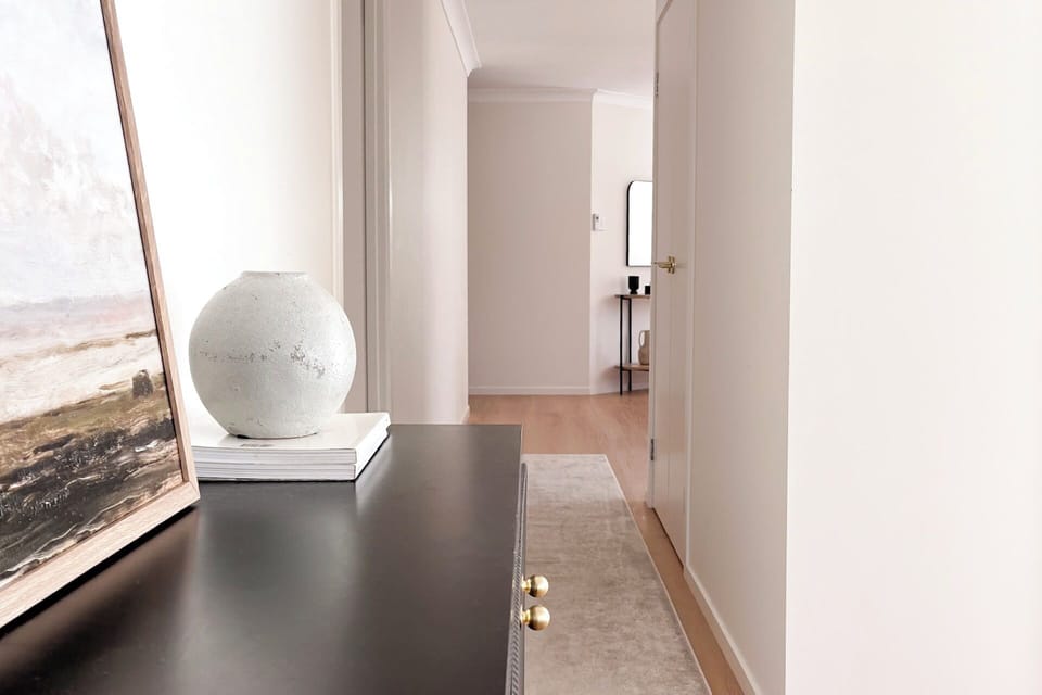 Living Room 2 : The hallway includes a console, artwork, rug runner and timber flooring, giving the home a clear path between living and bedrooms.