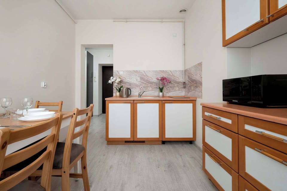A compact kitchen and dining area with wooden cabinets, a small table, and light-colored flooring creating a clean, practical layout.
