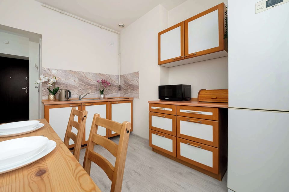 A small dining area with a wooden table set near a bright window, emphasizing natural light and simplicity.