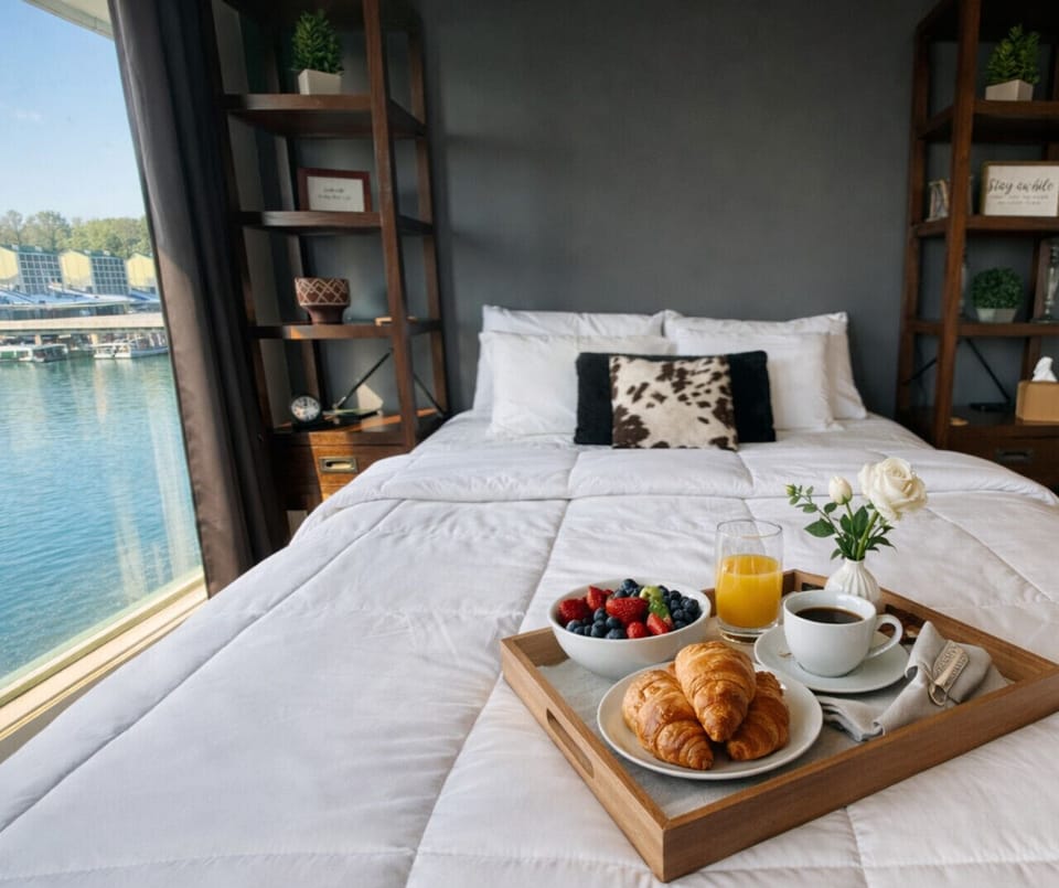 Chic lakefront bedroom with serene water views, cozy bedding, and a perfect setup for breakfast in bed.