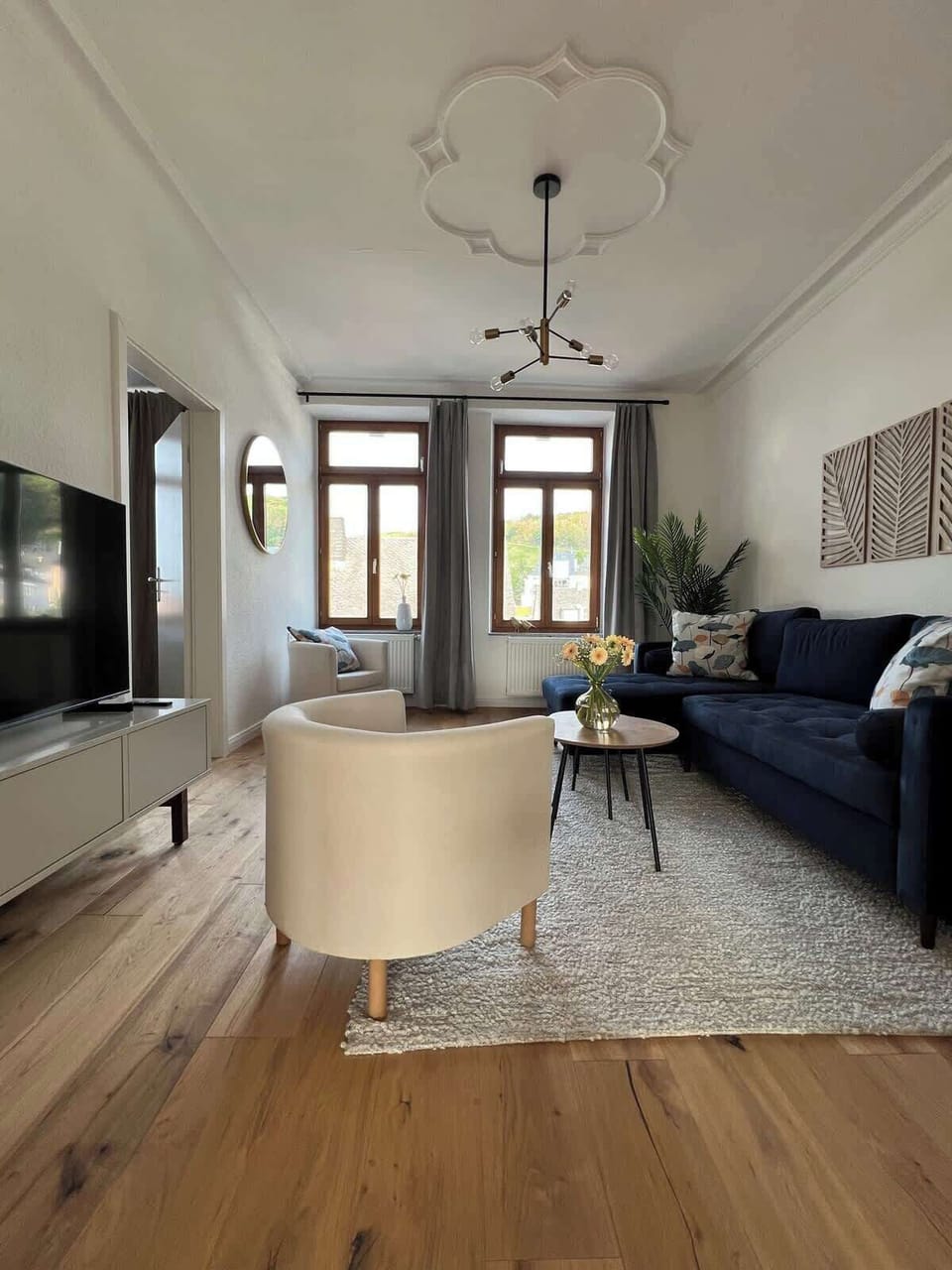 Helles Wohnzimmer mit gemütlichen Sitzgelegenheiten, Schlafcouch und Fernseher