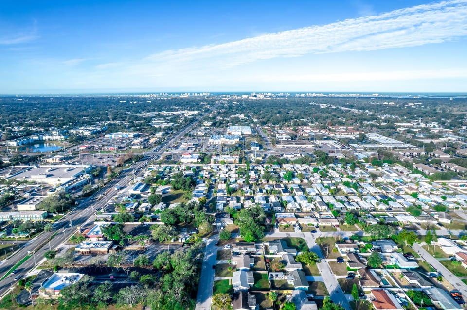 Aerial view showcasing the vibrant residential neighborhood with tree-lined streets and nearby city amenities stretching to the horizon.