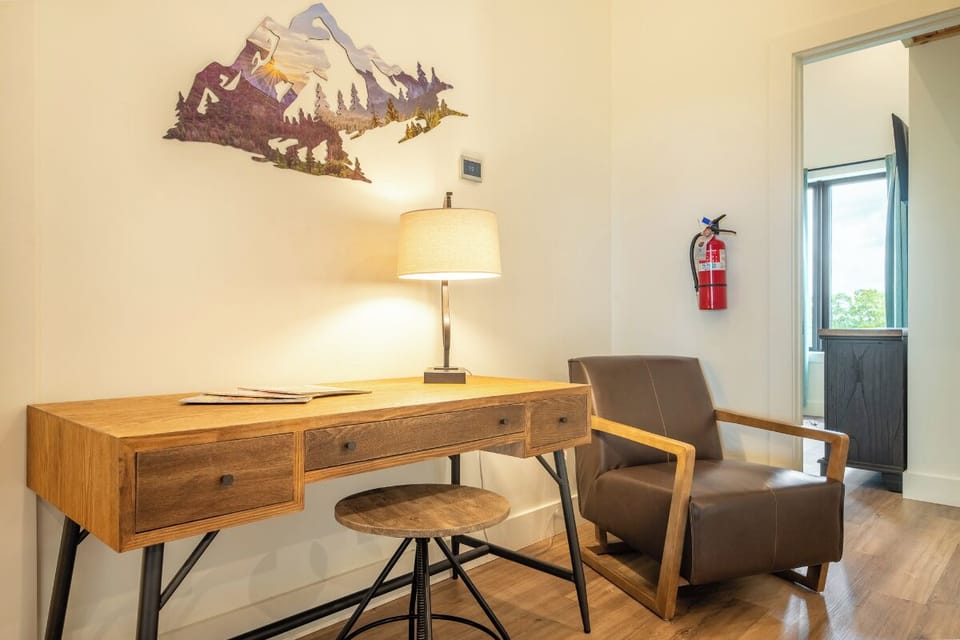 A versatile workspace awaits with a rustic wooden desk, warm lamp glow, and cozy chair—perfect for planning your next adventure or unwinding with a view.