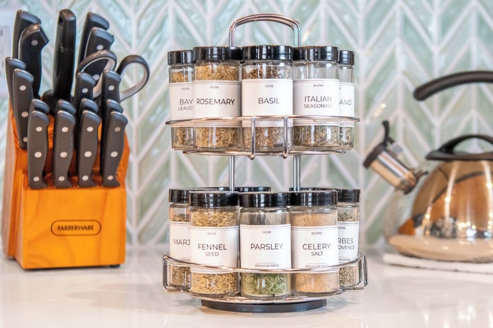 A thoughtfully stocked spice rack, quality knife set, and gleaming kettle await your culinary creations in this well-equipped kitchen space.