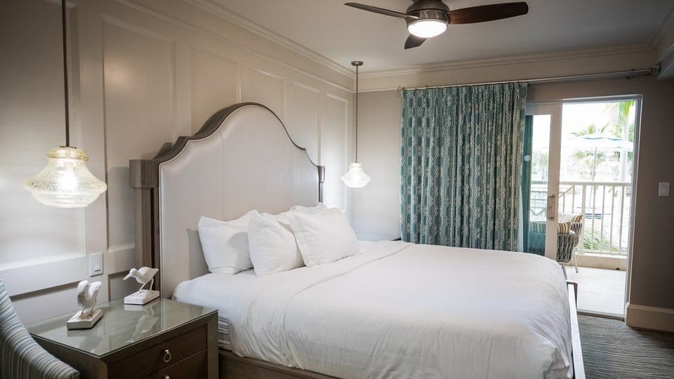 Elegant king bedroom with a padded headboard, bedside lighting, and a calm, modern coastal design.