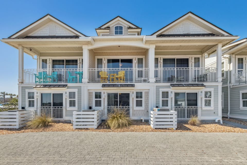 Charming coastal property with traditional architecture and covered porches, featuring multiple levels and balconies in a peaceful beachside setting.