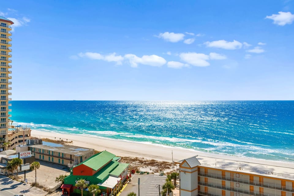Stunning beachfront location with pristine white sand and crystal-clear turquoise waters stretching to the horizon under bright blue skies.