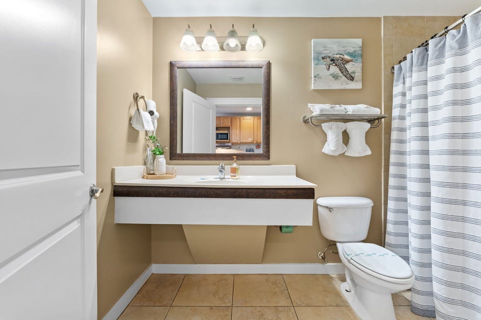 Refresh in your modern bathroom with floating vanity, coastal artwork, and fresh towels ready for your arrival.