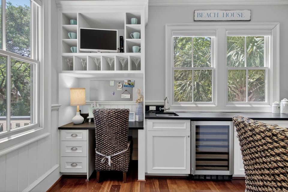 Your coastal workspace blends productivity with comfort, featuring elegant built-ins, a refreshing wet bar, and serene garden views.
