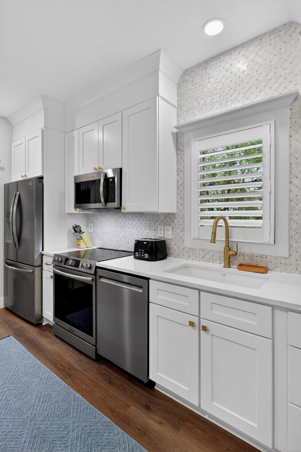 Your modern galley kitchen features pristine white cabinetry, gleaming stainless steel appliances, and elegant marble countertops for effortless meal preparation.