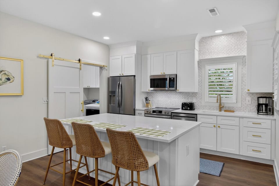 This bright, modern kitchen invites you to cook and gather with its spacious island, premium appliances, and warm coastal touches.
