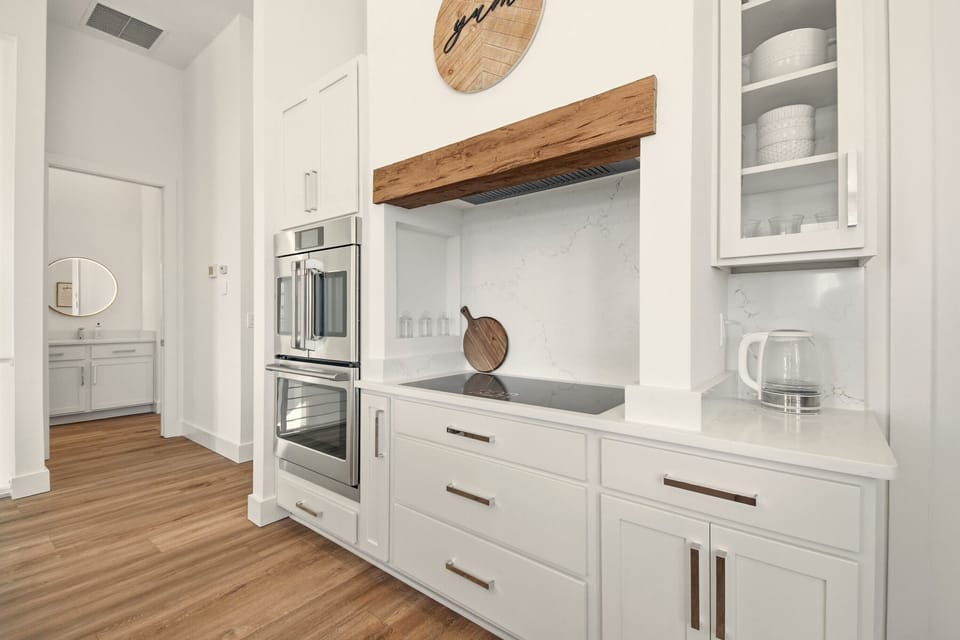 Start your morning here: coffee steaming on the quartz counter, sunlight on warm wood floors, and a chef-ready cooktop under that coastal beam. After the beach, gather for an easy dinner and dessert in a kitchen made for memories.
