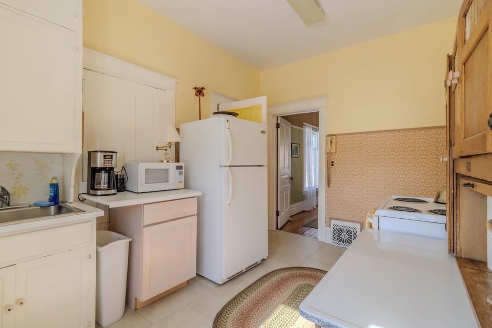 Kitchen - Open doorway leads into the dining room. The entry to the bathroom is directly to the right of the refrigerator. The stairs to the basement are directly across from the bathroom.