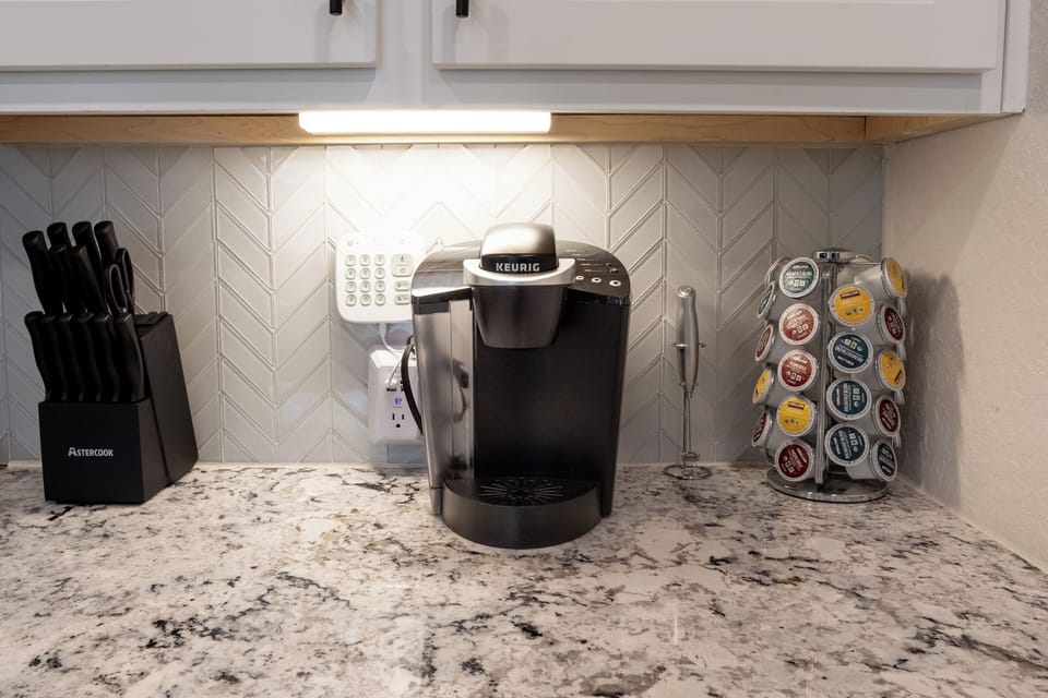 Keurig coffee maker with coffee pods, creamers, and sugar available.