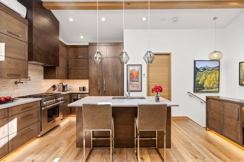Full-height cabinetry and a spacious island create the perfect gathering spot, framed by artwork celebrating Aspen's natural beauty.