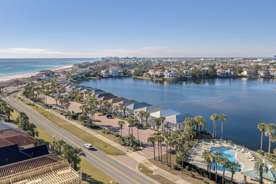 Aerial views showcasing the coastal setting—overlooking the lake, nearby homes, and the beach just moments away, with the community pool nestled along the waterfront.