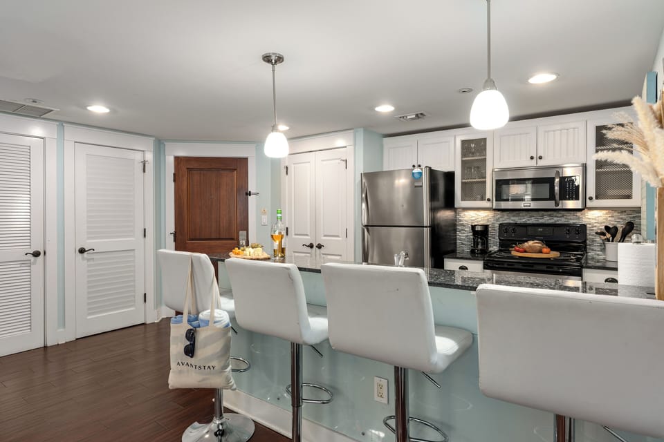 Bright kitchen with breakfast bar seating and stainless steel appliances.