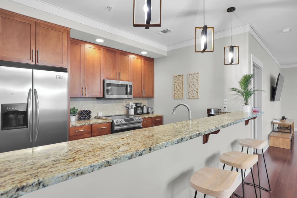 Modern kitchen with granite countertops, stainless steel appliances, and breakfast bar seating.