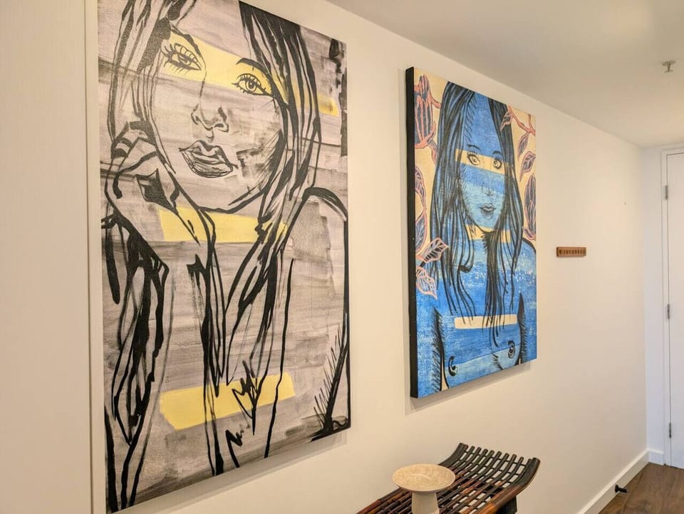 Two large-scale original canvases line the hallway — bold, expressive portrait works that make an immediate impression on arrival and set the tone for the apartment`s strong artistic identity.
