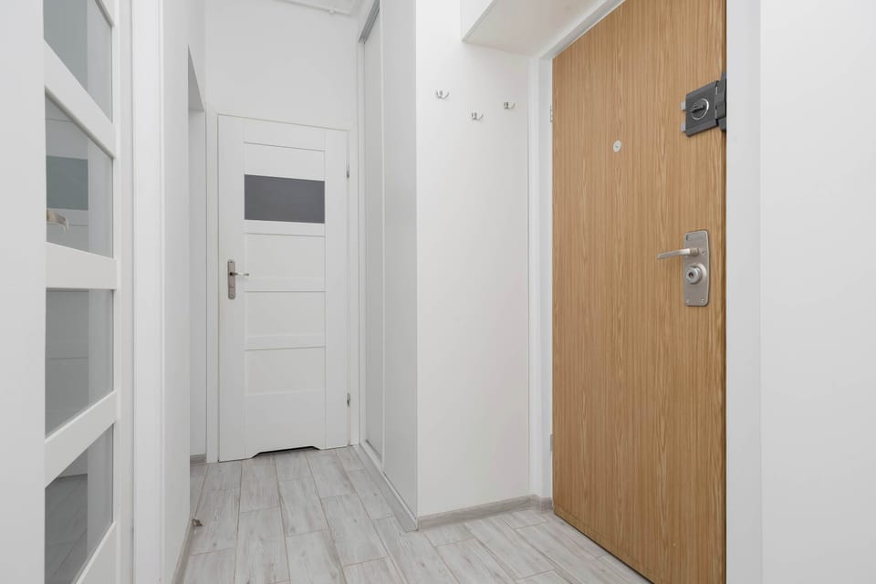 The entryway features a light wood front door and a white interior door leading to another room. A simple wall-mounted coat rack provides a practical spot for hanging jackets.