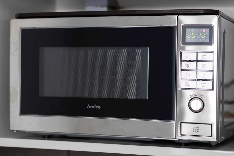 A stainless steel microwave is built into the kitchen cabinetry for convenience. The digital display and sleek buttons suggest a modern, easy-to-use appliance.