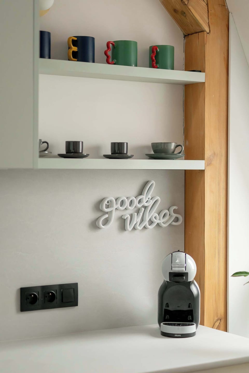 A dedicated coffee station includes a modern espresso machine and shelves stocked with colorful mugs. This thoughtful addition provides a convenient spot for guests to start their day.