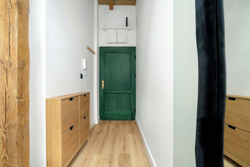 he entrance hallway is lined with warm wood paneling and features a dark green door. A long mirror and minimalist storage solutions keep the entryway functional and tidy.