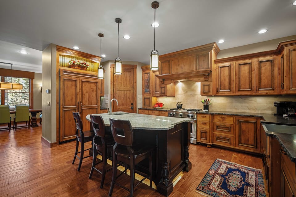 Your chef dreams come alive in this stunning gourmet kitchen with rich wood cabinets, granite island seating, and premium appliances.