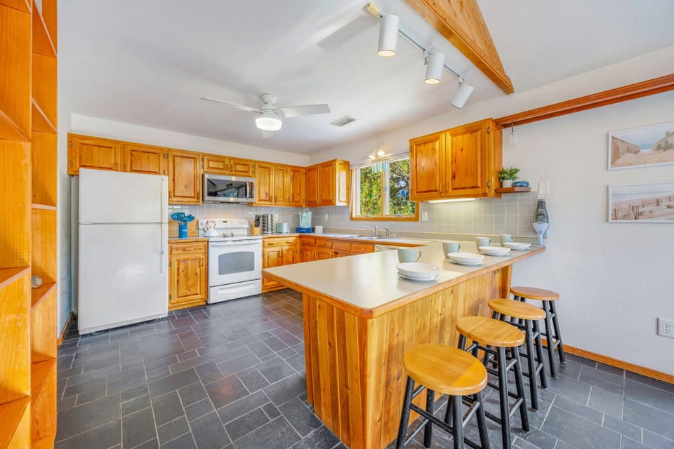 Your fully equipped kitchen features rich wood cabinetry, modern appliances, and a breakfast bar where you can savor morning coffee together.