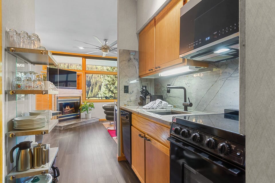 Your fully equipped kitchen features modern appliances, marble countertops, and natural light streaming through large windows—perfect for preparing meals while enjoying views of the surrounding greenery.