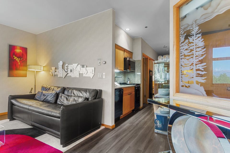 Cozy yet stylish, this open-concept space blends modern comfort with mountain charm. Settle into the sleek leather sofa, whip up a meal in the well-equipped kitchenette, and gaze through custom tree-art panels to real mountain vistas beyond.