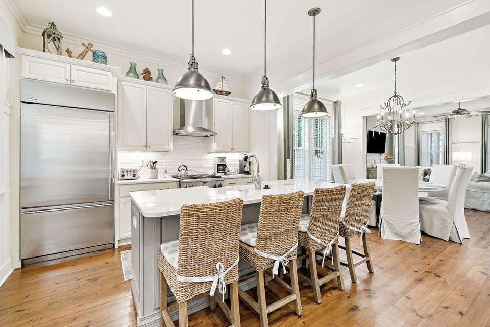 Your gourmet kitchen awaits with marble countertops, stainless steel appliances, and coastal wicker seating—perfect for morning coffee or evening conversations.